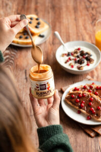 pâtes-à-tartiner-degustation-buenuts-petit-dejeuner-happy-hours-en-biovallee-nouveautes-2026 Main tenant une cuillère recouverte de pâte à tartiner Buenuts Happy Hours